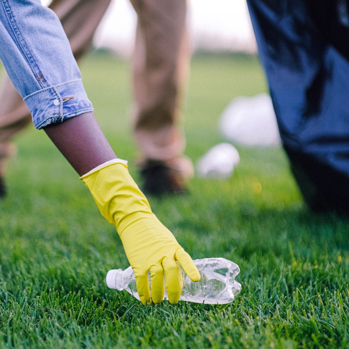 Gloved hand collecting a plastic bottle during residential cleanup in Hobe Sound, FL